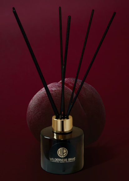 Amber Reed Diffuser with black fibre reeds with plum background