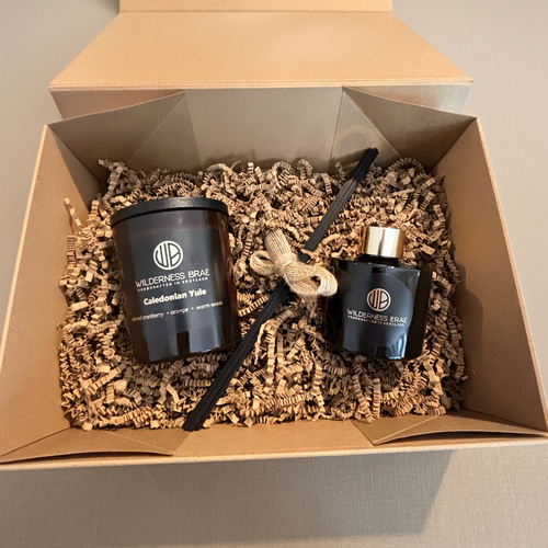 A candle & diffuser gift set from Wilderness Brae in a kraft paper box filled with crinkle paper packaging.