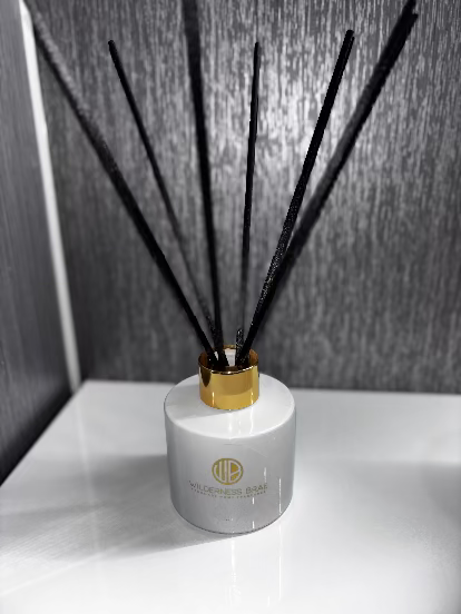 white and gold reed diffuser with black reeds in white bathroom cabinet