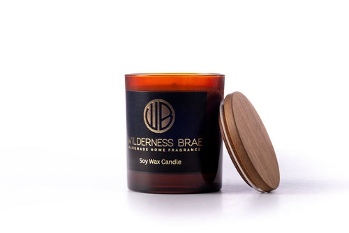 AMBER CANDLE WITH BLACK AND GOLD LABEL ON WHITE BACKGROUND wooden lid off 