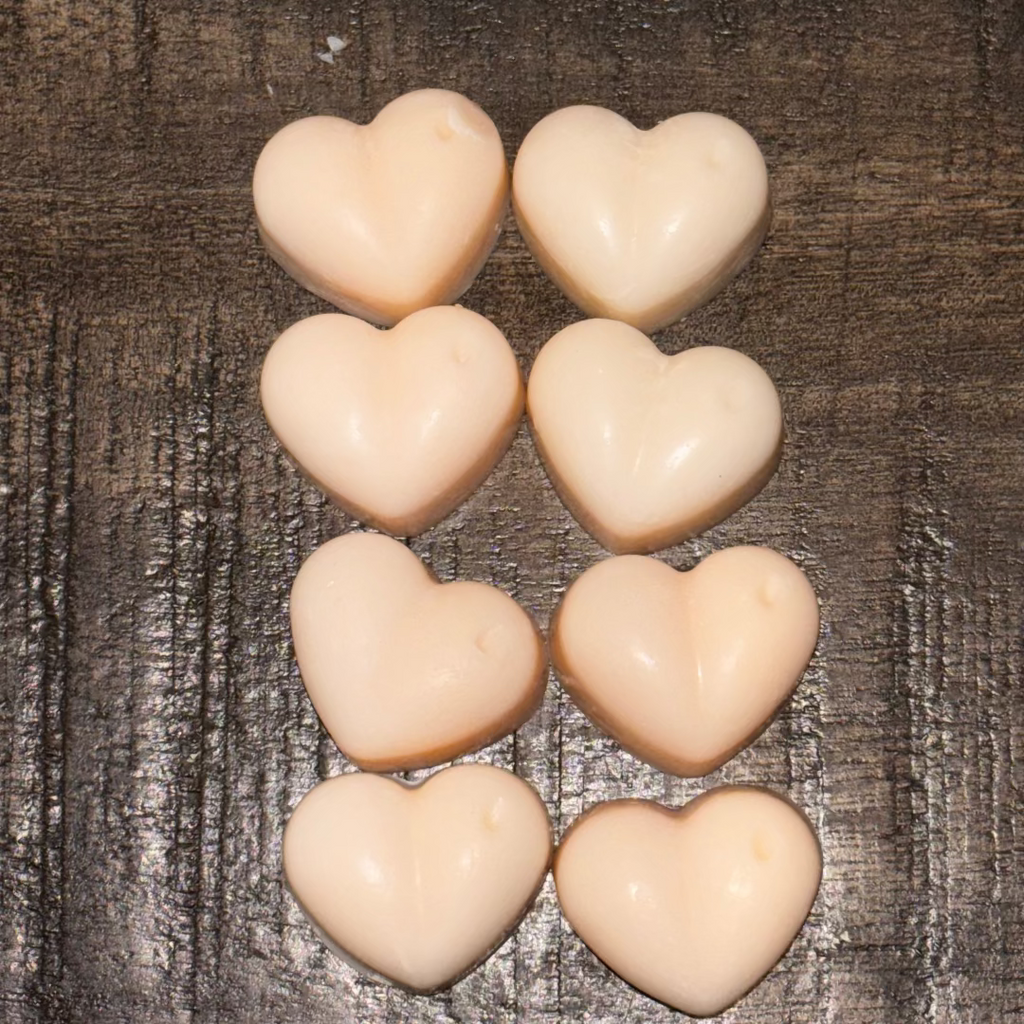 Heart-shaped wax melts arranged in a pattern on a wooden surface