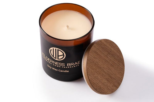 Caledonian Yule soy candle, handcrafted in Scotland by Wilderness Brae - Amber jar with wooden lid off, shot from above on white background 
